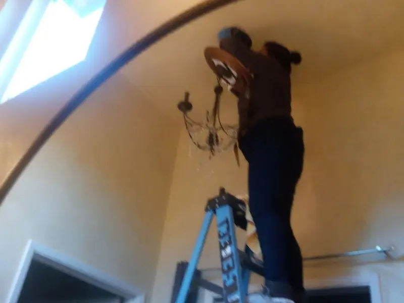 Electrician installing a chandelier in a Antis residence